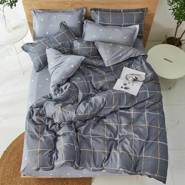 Комплект постільної білизни сірого кольору у клітинку з полікатону, що розстелений на ліжку, демонструючи лаконічний дизайн та фактуру тканини.